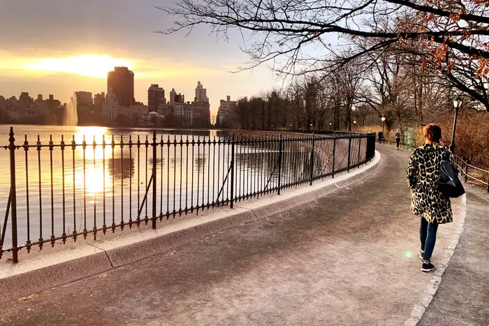 A photo of a woman walking by the reservoir in Central Park